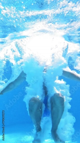 An energetic dive into a swimming pool. Handsome young man swimming in pool, underwater view Vertical video