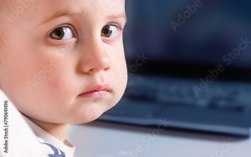 Portrait of beautiful baby watching computer at home. Copy space for text or design.