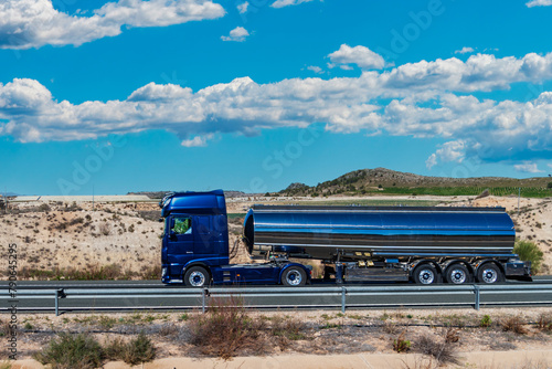 Tanker truck for transporting food liquids traveling on a highway, side view.