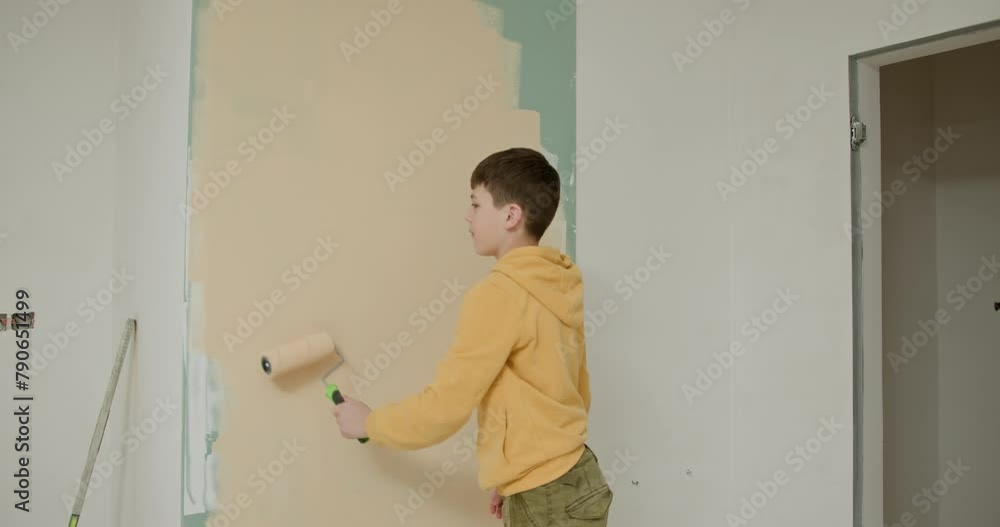 Children are home designers. Home renovation concept. Cute boy with a paint roller. Kid helps parents to paint wall. Repair of a new house. Child boy painted the wall with paint in the apartment Children are home designers. Home renovation concept. Cute boy with a paint roller. Kid helps parents to paint wall. Repair of a new house. Child boy painted the wall with paint in the apartment