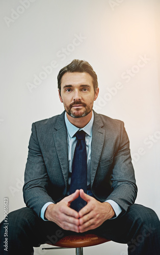 Business, portrait and mature man on office chair with triangle hands, mindset or power pose on wall background. Face, goals or male lawyer at law firm with ambition, career or fierce attitude