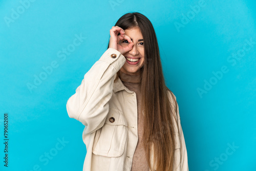 Young caucasian woman isolated on blue background showing ok sign with fingers