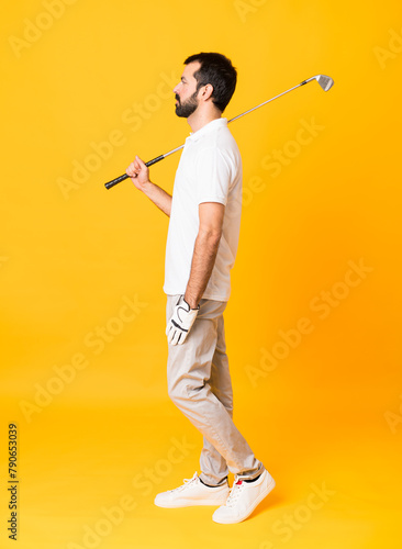 Full-length shot of man over isolated yellow background playing golf