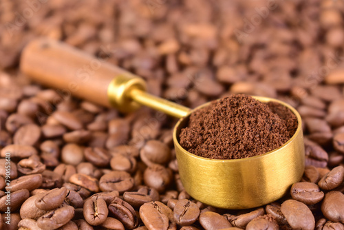 Ground coffee in a spoon on a background of coffee beans. Close-up. Selective focus.
