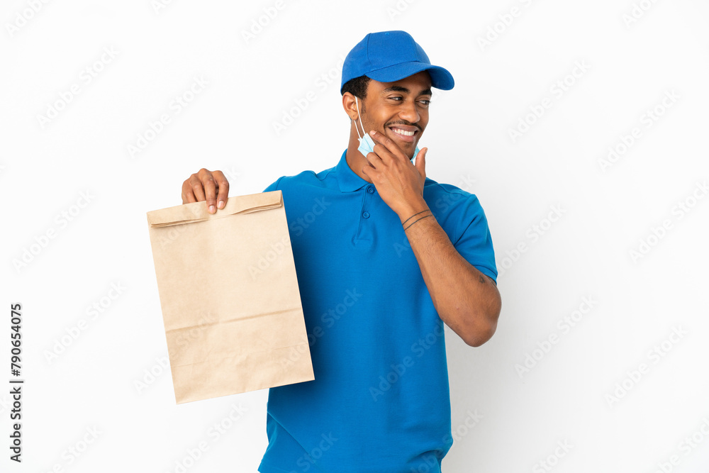 African American man taking a bag of takeaway food isolated on white background looking to the side and smiling African American man taking a bag of takeaway food isolated on white background looking to the side and smiling