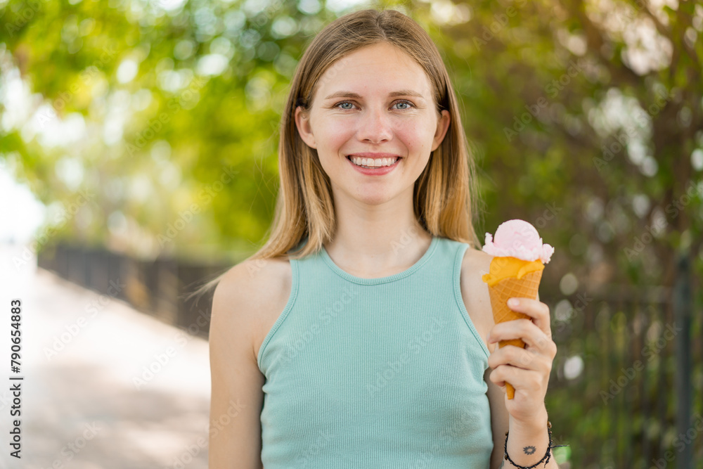 Young blonde pretty woman with a cornet ice cream at outdoors smiling a lot Young blonde pretty woman with a cornet ice cream at outdoors smiling a lot