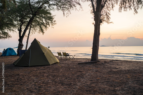 Morning sunrise beside camp and tents under tree, golden light at sea, Outdoor lifestyle concept.