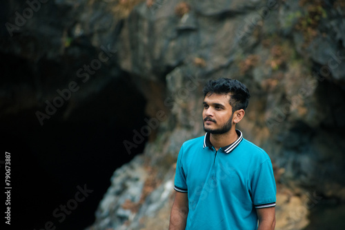 Young indian man wearing blue t-shirt standing in a cave. © DiversePixels