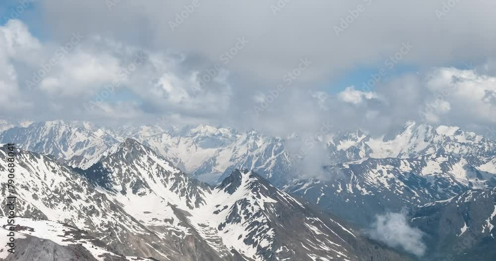 Air flight through mountain clouds over beautiful snow-capped peaks of mountains and glaciers. Air flight through mountain clouds over beautiful snow-capped peaks of mountains and glaciers.
