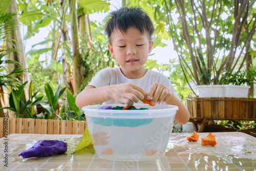 Happy little Asian school kid studying science, making A Boat Float Density Science Experiment with Modeling clay, Home based Learning, Kid-friendly fun and easy science experiments at home concept