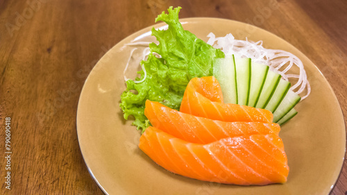 Fresh Sliced Salmon Sashimi is a Japanese specialty that uses fresh raw fish meat without bones, served with grated radish, zucchini, soy sauce, lime wedges, and wasabi.