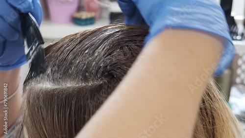 Blonde attraktive Frau, die sich Haarfarbe mit einem Pinsel aufträgt