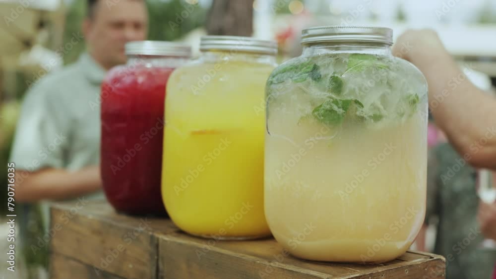 A row of jars with various fruit juices on a wooden table A row of jars with various fruit juices on a wooden table