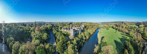 An aerial panorama reveals the majestic Lismore Castle in County Waterford, Ireland, set against a flawless spring sky