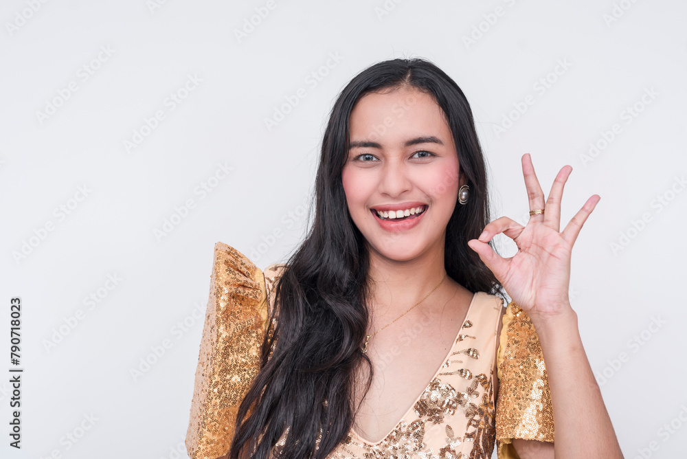Joyful Filipino woman in traditional Filipiniana dress making OK sign, isolated on white background Joyful Filipino woman in traditional Filipiniana dress making OK sign, isolated on white background
