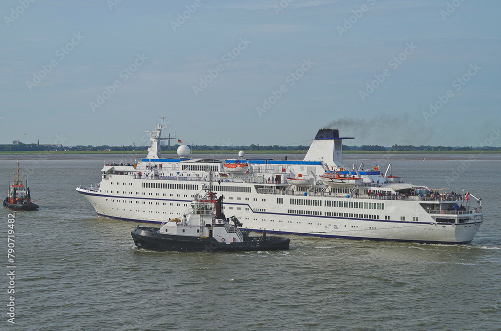 Small classic cruiseship cruise ship ocean liner Berlin arrival into Bremerhaven port, Germany with tug boats and marine traffic Small classic cruiseship cruise ship ocean liner Berlin arrival into Bremerhaven port, Germany with tug boats and marine traffic