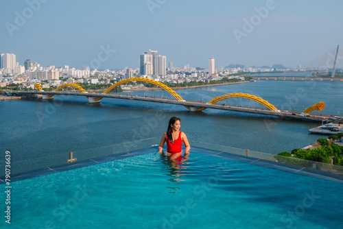 Asian people relaxing in the swimming pool with Han River view and Dragon Bridge in  Da Nang , Vietnam