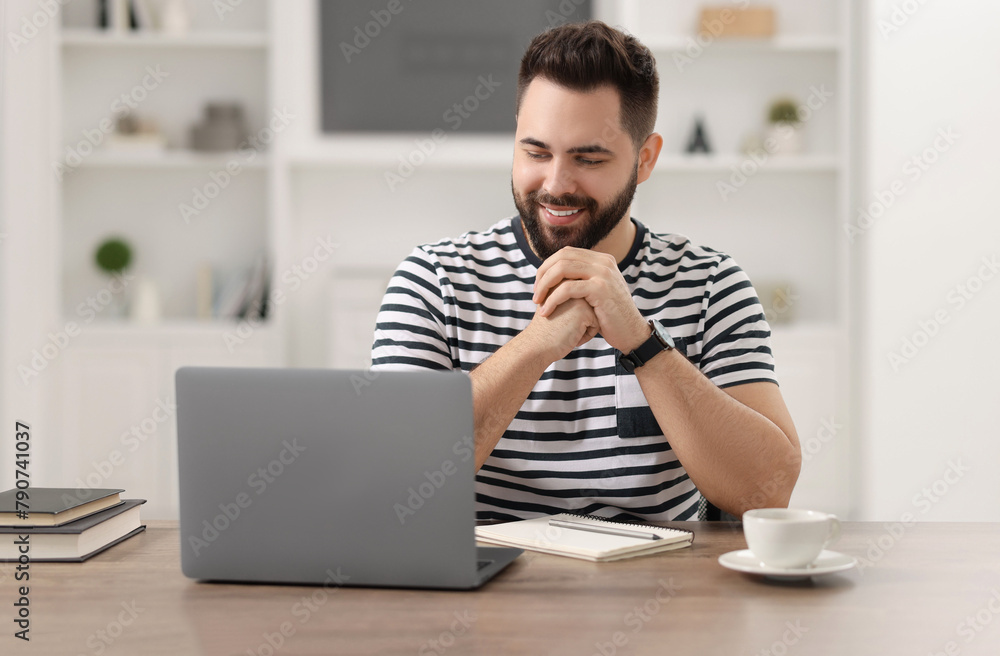 Young man watching webinar at table in room Young man watching webinar at table in room