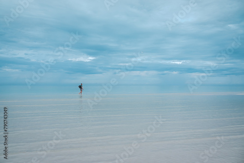 Solitary Figure Walking in Calm Seaside Waters in Holbox in Mexico