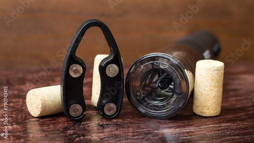 An electric corkscrew and wine bottle caps lie on a dark wood table, preparing holiday. photo