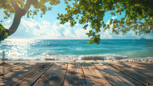 A peaceful perspective of a tropical beach from a sunlit wooden deck framed by overhanging branches and leaves. photo