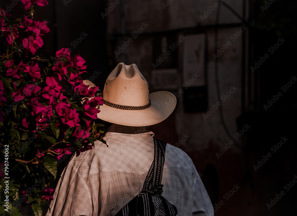 Obraz premium Mexican Man in White Hat Standing Near Bright Pink Flowers in San Miguel de Allende, Mexico