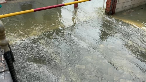 Turbid water fast flow on paved surface, flood on the road photo