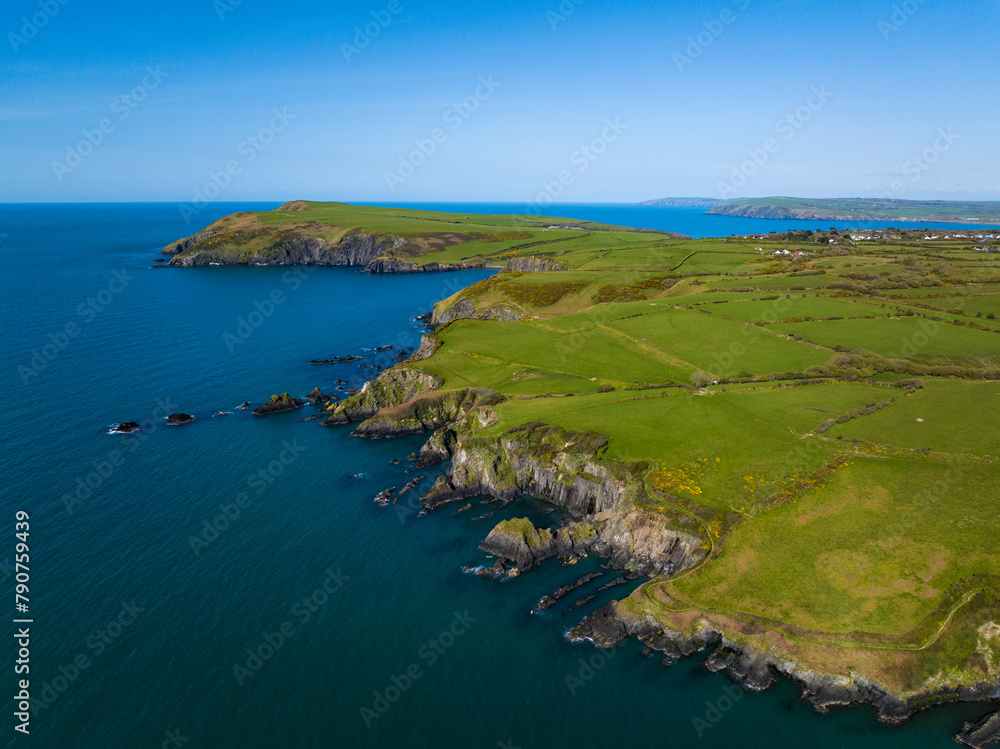 Aerial shot travelling along rocky coastline and cliffs of West Wales near Fishguard on windy but sunny day