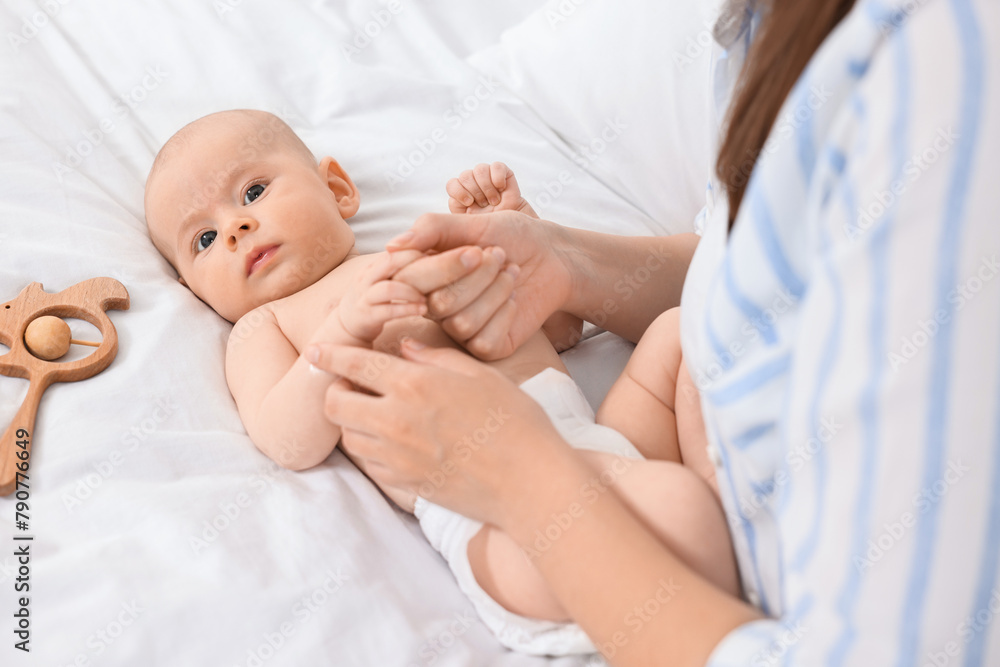 Woman applying body cream onto baby`s skin on bed, closeup Woman applying body cream onto baby`s skin on bed, closeup