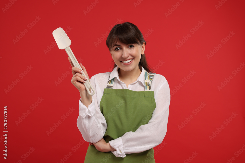 Happy professional confectioner in apron holding spatula on red background Happy professional confectioner in apron holding spatula on red background