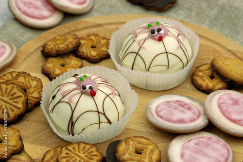 Dessert in the form of cakes with funny spiders. Soufflé cake and cookies on a wooden board. Dessert close-up.