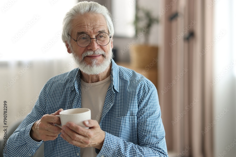 Portrait of happy grandpa with glasses and cup of drink indoors Portrait of happy grandpa with glasses and cup of drink indoors