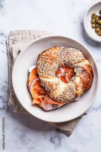 Breakfast bagel with salmon, cream cheese, capers and onions, white background.