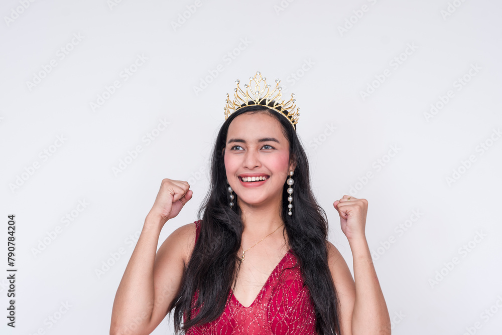 Southeast Asian beauty queen celebrates victory with fists pumped, wearing a gold tiara Southeast Asian beauty queen celebrates victory with fists pumped, wearing a gold tiara