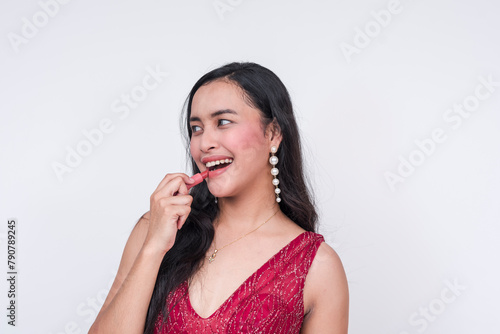 Southeast Asian woman in elegant attire applying lipstick  isolated on white