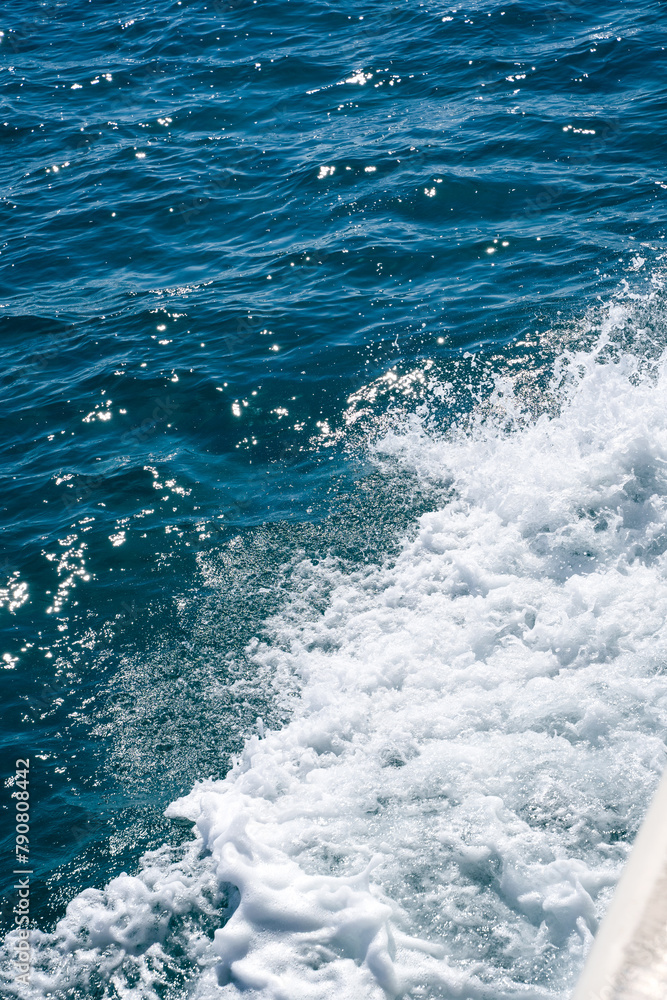 Splash of white foam in the water created by movement of a boat in the sea