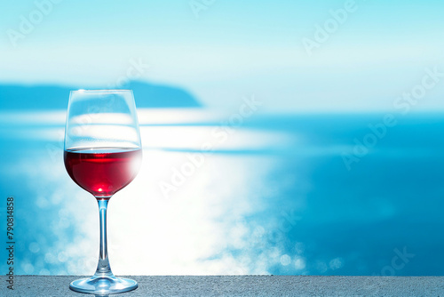 glass of red wine on the beach, beautiful blue sky over the ocean or sea, summer vacation or holiday