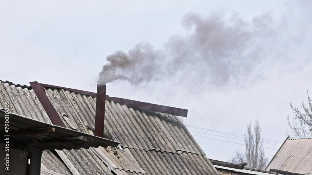 Black smoke coming out from rustic bathhouse chimney steel pipe, the concept of heating with low quality coal or rags. Black smoke coming out from rustic bathhouse chimney steel pipe, the concept of heating with low quality coal or rags.