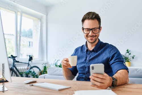 Adult man using mobile phone while working from home © baranq
