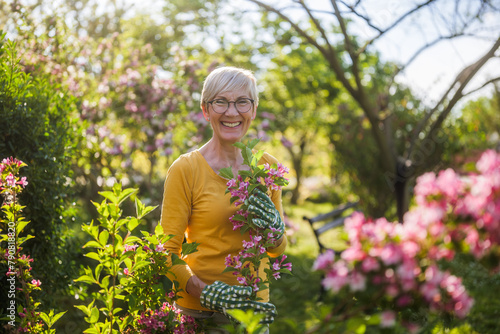 Happy senior woman enjoys looking at flowers in her garden.