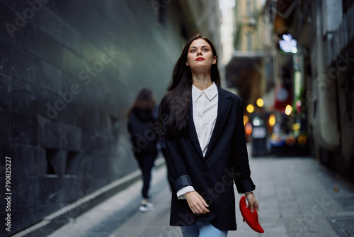 Fashion woman tourist in stylish clothes in a jacket and red beret walking down a narrow city street flying hair and happy travel, French style, cinematic color, retro style. © SHOTPRIME STUDIO
