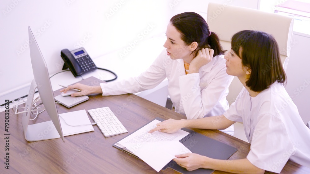 Colleagues discussing about medical report using computer in the clinic Colleagues discussing about medical report using computer in the clinic