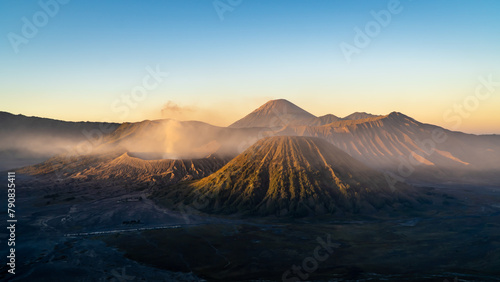 Volcano spewing smoke into sky among natural mountain landscape photo