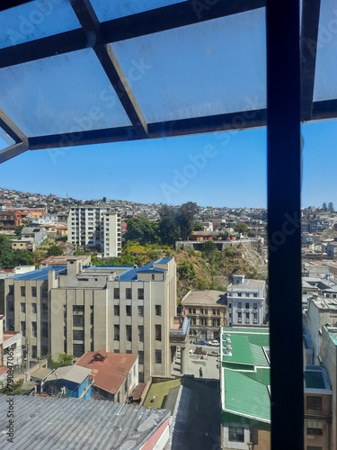 Foto tirada da janela do elevador em Valparaíso, Chile, em um dia ensolarado. Vista panorâmica da vibrante arquitetura da cidade costeira, o céu azul. Perfeita para promover o turismo