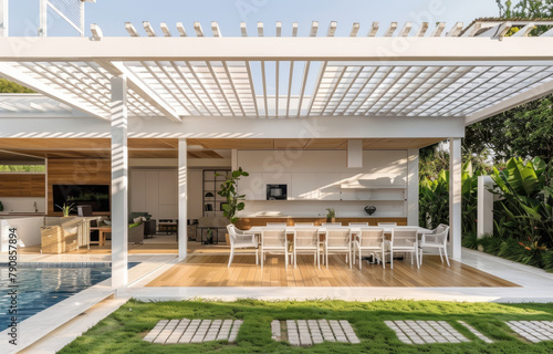 A white wood pavilion with an outdoor dining area and wooden deck, surrounded by green grass near the pool in front of a modern minimalist house.