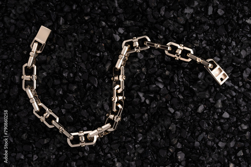 Gold bracelet on a background of black volcanic stones. Beautiful chain bracelets on black background. Gold links hand bracelet.
