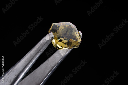 Close-up of a large 6-carat alexandrite stone. Alexandrite chrysoberyl close-up. Large alexandrite gemstone held with tweezers.