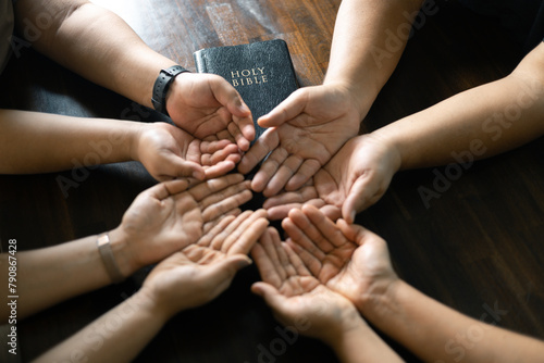 Woman gathered with her Christian friends in church, Bible close as they joined in prayer, feeling warmth of their religious family bond within group. © doidam10