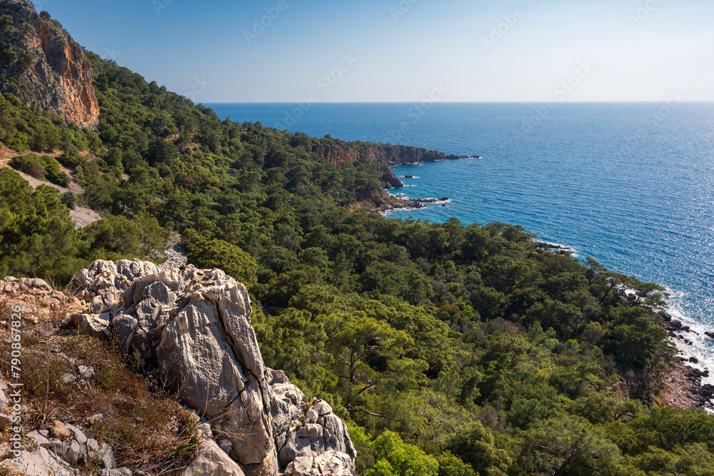Landscape with rocky cliffs, sandy beach, turquoise sea and vivid vegetation on hills, Lycian Way, Turkey