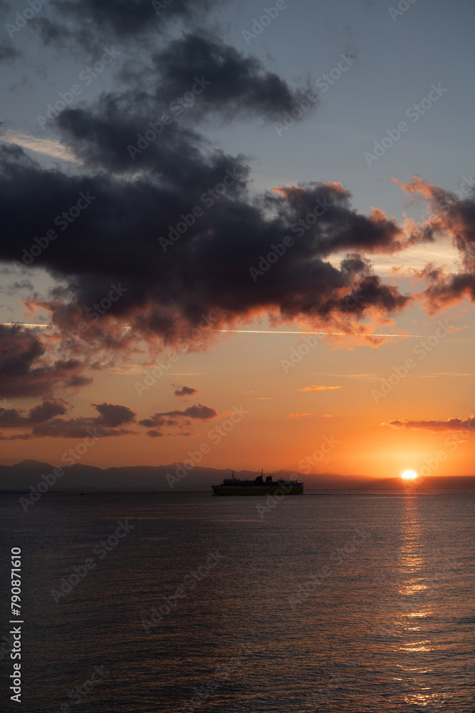 Verticle wide angle of a cruise ship voyage against calm dramatic clouds during sunrise in zante, Zakynthos, Greece